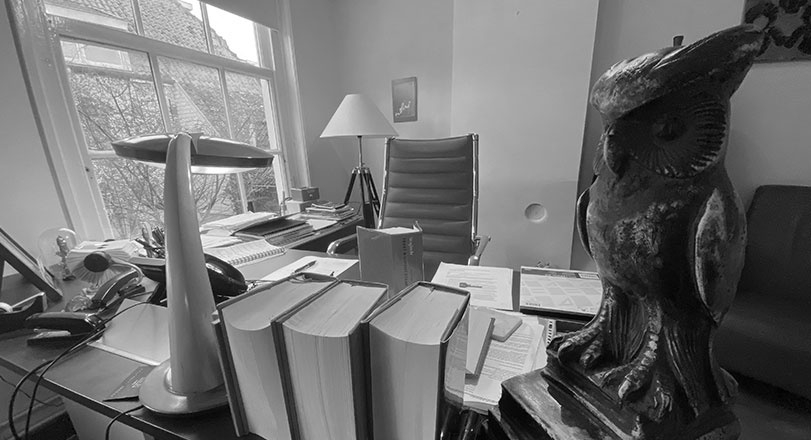 De werkkamer van Peters Advocatuur met wetboeken en de uil op het bureau